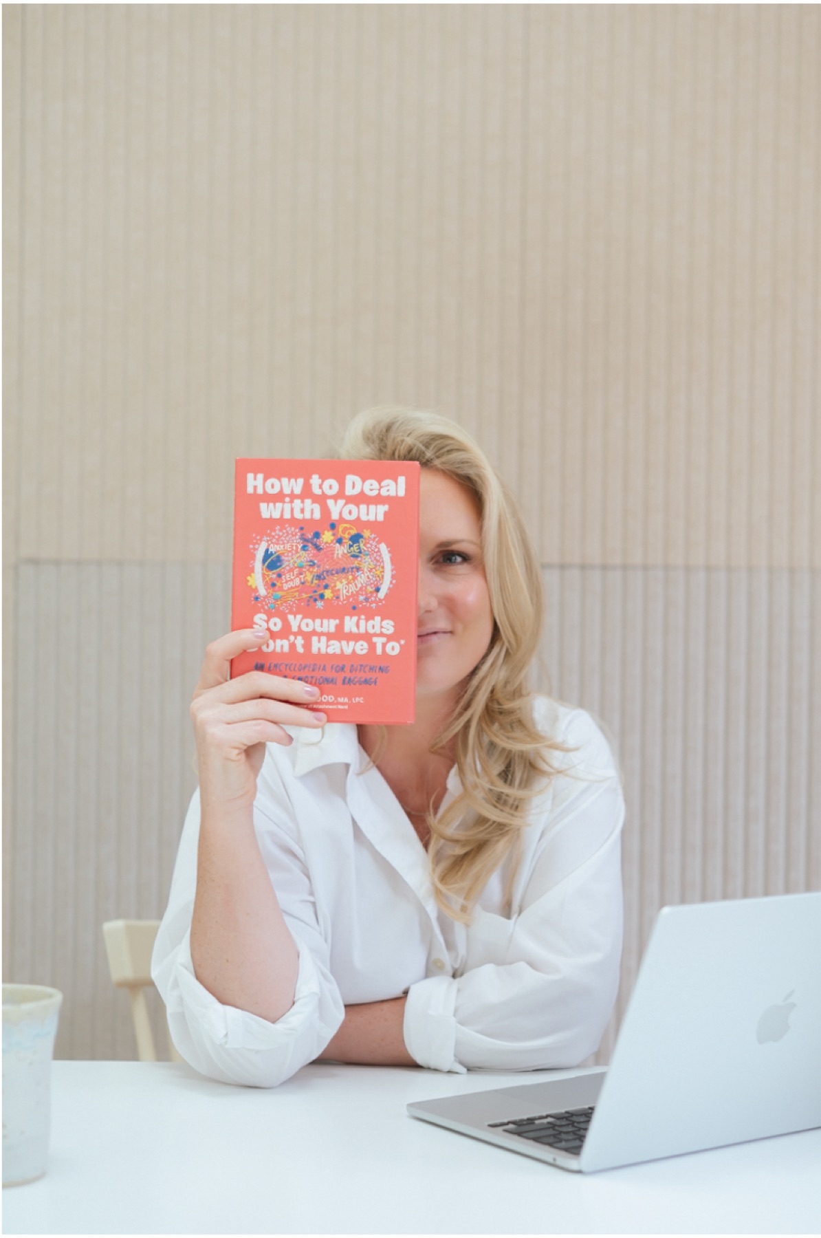 Caitlyn Skolnick, therapist for moms in New Jersey, holding a parenting book