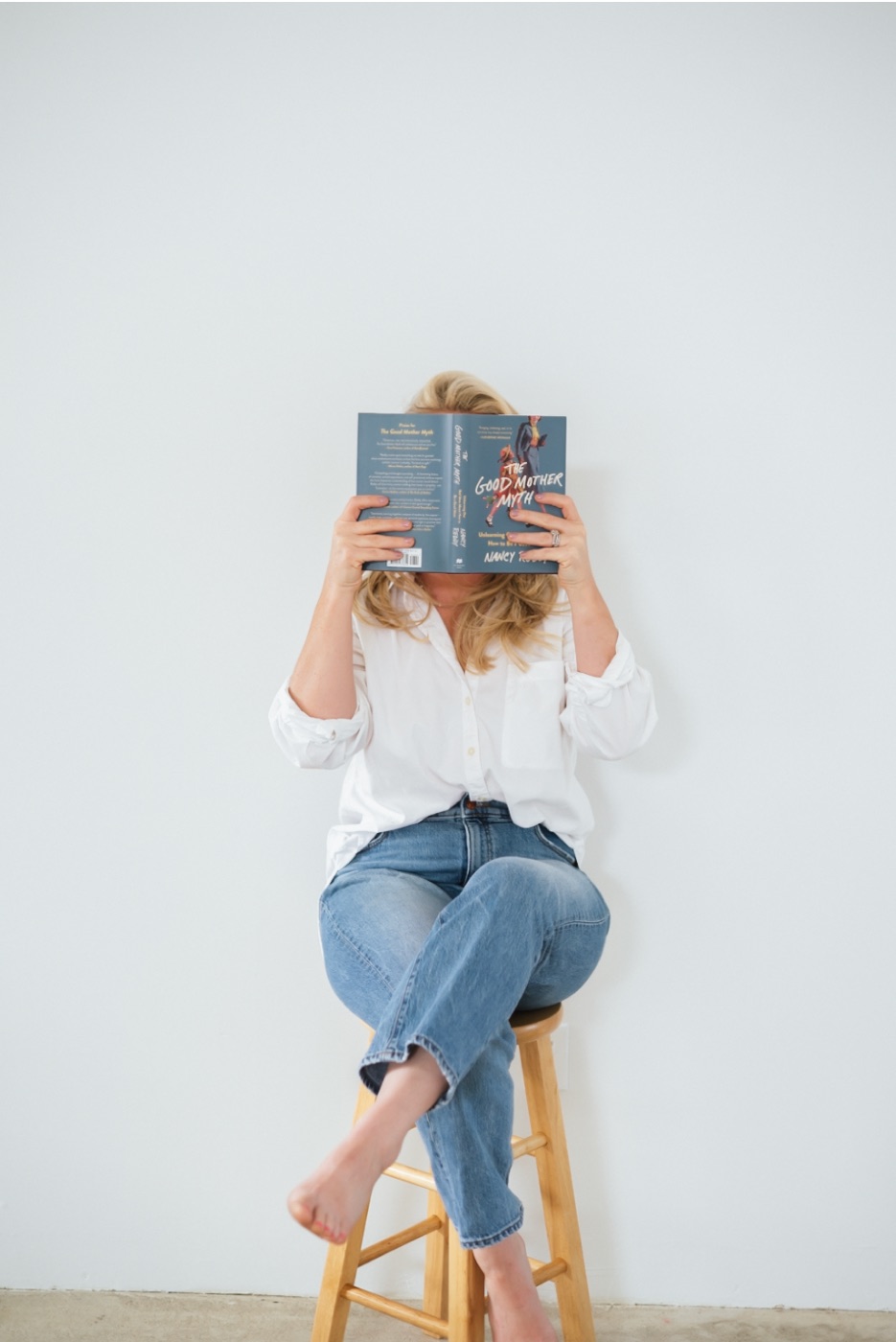 Caitlyn reading a parenting book on a stool