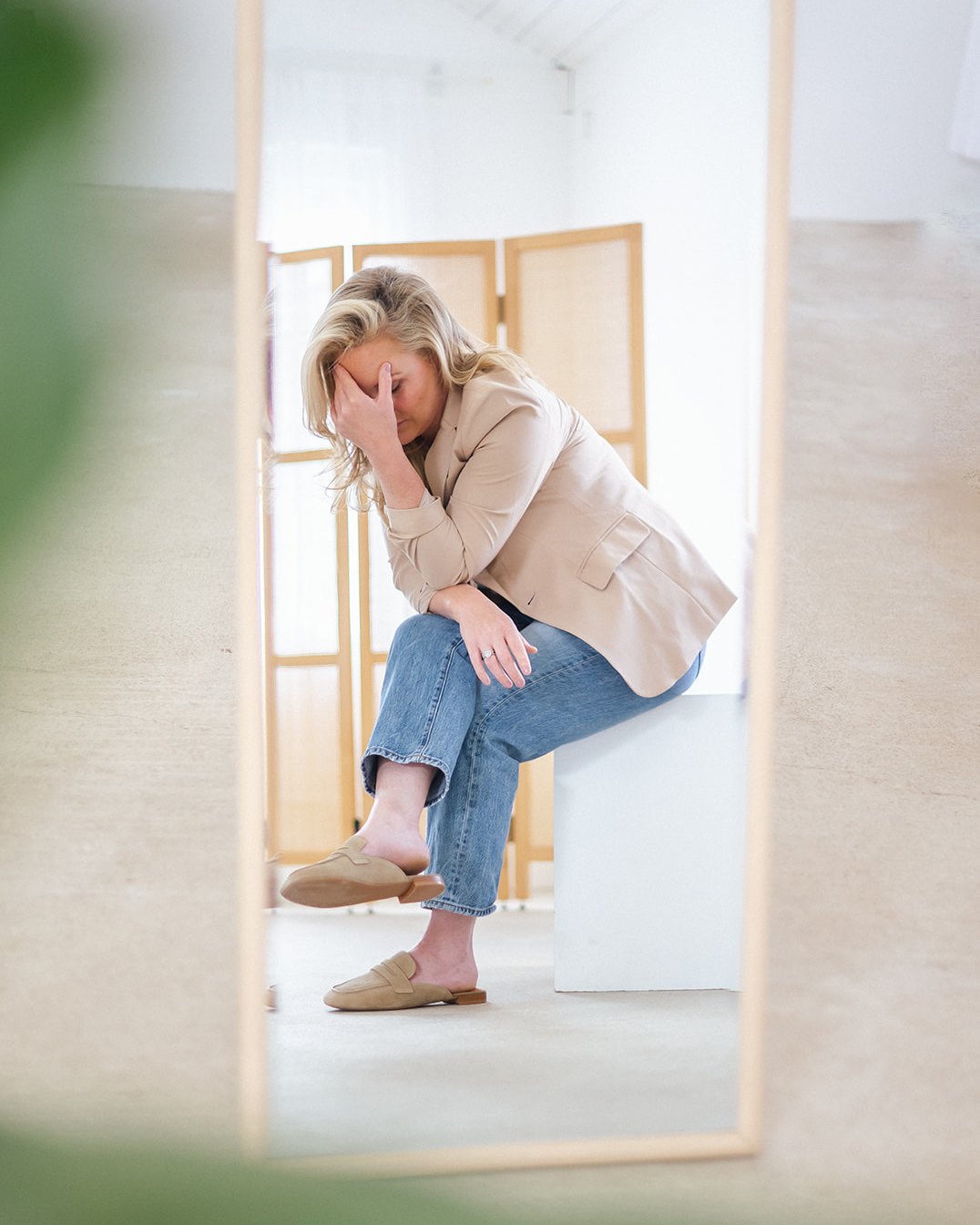 Caitlyn Skolnick reflected in a mirror, head in hand — infertility and IVF counseling in New Jersey